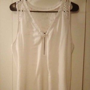 Size large, sleeveless, off white with zipper front and pretty design on back